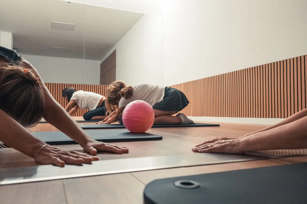 Aula de pilates em grupo no estúdio, com tapetes no chão e bolas de exercício