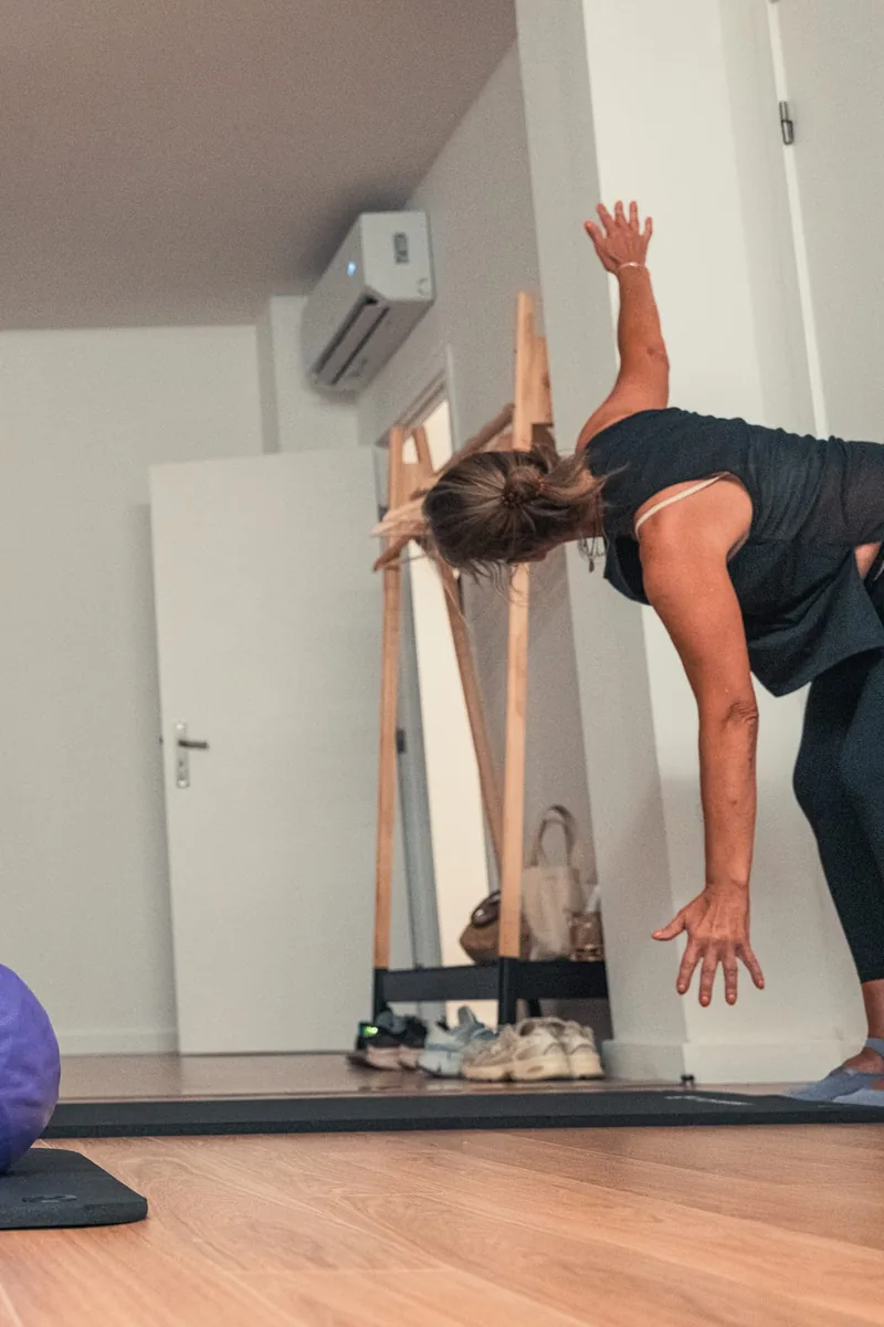 Exercício de pilates de pé no estúdio, junto à parede de madeira