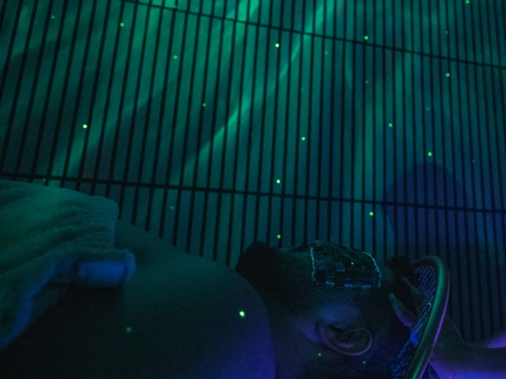 Ritual de Head Spa numa sala de luz azul e verde, com o arco de cobre sobre a cabeça